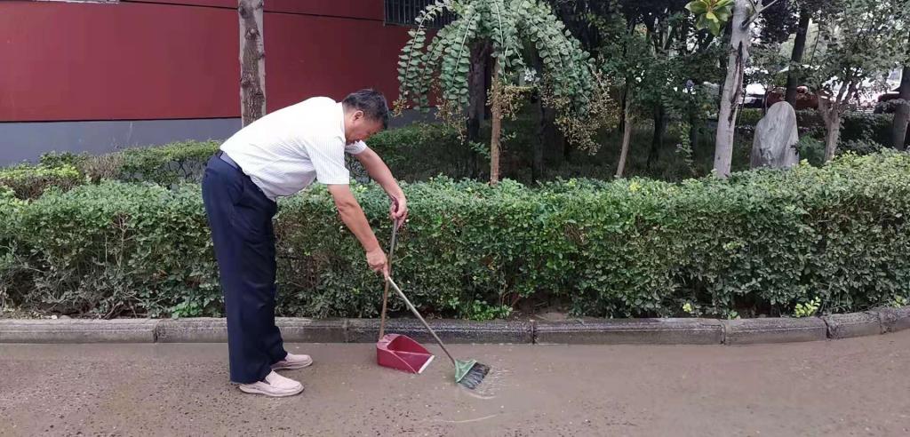 王校长用扫帚、撮斗开始排水